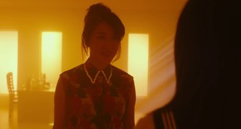 Movie still from “Antiporno” (2016), directed by Sion Sono – A young woman in a dress and a necklace smiles for the camera; Close Up shot, Over the shoulder angle