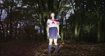 Movie still from “Antiporno” (2016), directed by Sion Sono – A woman in a sailor suit standing in the woods; Wide shot, Low angle