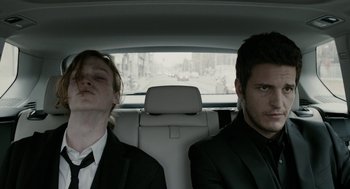 Two men in suits in the back of a car