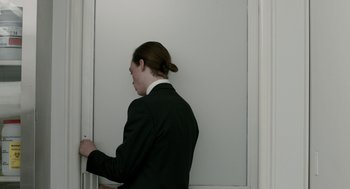 A man in a suit is standing in front of a door