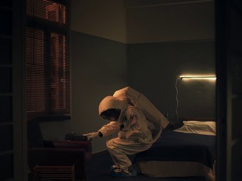 A person in a white suit is sitting on a bed