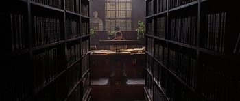 Movie still from “Apt Pupil” (1998), directed by Bryan Singer – A person sitting at a desk in a library; Wide shot, High angle