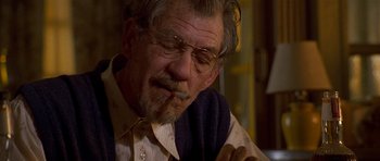 Movie still from “Apt Pupil” (1998), directed by Bryan Singer – An older man smoking a cigarette while wearing glasses; Close Up shot, Over the shoulder angle