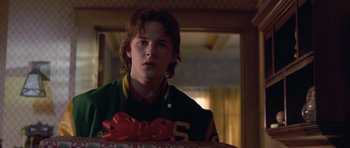 Movie still from “Apt Pupil” (1998), directed by Bryan Singer – A young man holding a gift box in a room; Close Up shot, Over the shoulder angle