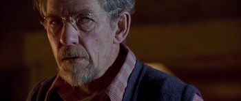 Movie still from “Apt Pupil” (1998), directed by Bryan Singer – An older man wearing glasses and a plaid shirt; Close Up shot, Over the shoulder angle