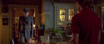 Movie still from “Apt Pupil” (1998), directed by Bryan Singer – A man and a woman are standing in a living room; Medium shot, Low angle