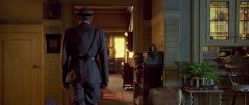Movie still from “Apt Pupil” (1998), directed by Bryan Singer – A man in a uniform walking in a room; Wide shot, Low angle