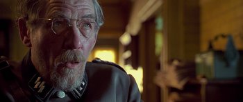 Movie still from “Apt Pupil” (1998), directed by Bryan Singer – An older man wearing glasses and wearing a uniform; Close Up shot, Over the shoulder angle