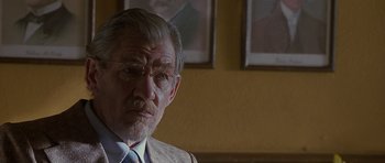 Movie still from “Apt Pupil” (1998), directed by Bryan Singer – An older man wearing glasses and a suit; Close Up shot, Over the shoulder angle