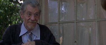 Movie still from “Apt Pupil” (1998), directed by Bryan Singer – An older man wearing glasses and a sweater; Close Up shot, Over the shoulder angle