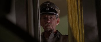 Movie still from “Apt Pupil” (1998), directed by Bryan Singer – An old man in a german military uniform looking out of a window; Close Up shot, Over the shoulder angle