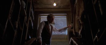 Movie still from “Apt Pupil” (1998), directed by Bryan Singer – An old man standing in front of a window in a room; Medium shot, Low angle