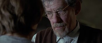 Movie still from “Apt Pupil” (1998), directed by Bryan Singer – An older man wearing glasses and a brown sweater; Close Up shot, Over the shoulder angle