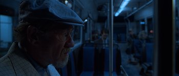 Movie still from “Apt Pupil” (1998), directed by Bryan Singer – An older man wearing a hat riding a bus; Close Up shot, Over the shoulder angle