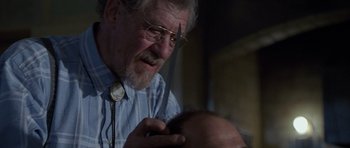Movie still from “Apt Pupil” (1998), directed by Bryan Singer – An older man is cutting another man's hair; Close Up shot, Over the shoulder angle