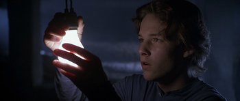 Movie still from “Apt Pupil” (1998), directed by Bryan Singer – A young man holding a cell phone in his hand; Close Up shot, Low angle
