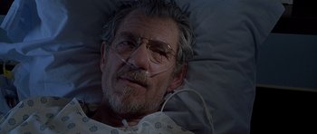 Movie still from “Apt Pupil” (1998), directed by Bryan Singer – An older man laying in a hospital bed with an oxygen mask on; Close Up shot, High angle