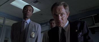 Movie still from “Apt Pupil” (1998), directed by Bryan Singer – A man in a suit and tie standing next to another man in a suit and tie; Close Up shot, Low angle