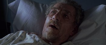 Movie still from “Apt Pupil” (1998), directed by Bryan Singer – An old man with a beard and glasses is laying in a hospital bed; Close Up shot, Low angle