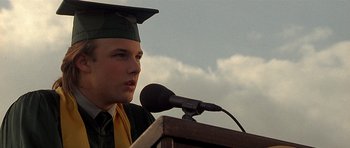Movie still from “Apt Pupil” (1998), directed by Bryan Singer – A man in a cap and gown is giving a speech; Close Up shot, Low angle