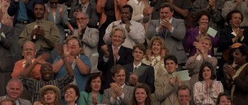 Movie still from “Apt Pupil” (1998), directed by Bryan Singer – A group of people sitting in a crowd clapping; Medium shot, Over the shoulder angle