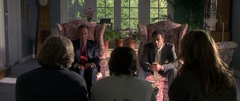 Movie still from “Apt Pupil” (1998), directed by Bryan Singer – A group of people sitting in a living room talking; Medium shot, Low angle