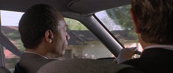 Movie still from “Apt Pupil” (1998), directed by Bryan Singer – A man sitting in the driver's seat of a car looking out the window; Close Up shot, Low angle