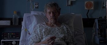 Movie still from “Apt Pupil” (1998), directed by Bryan Singer – An older man in a hospital bed is listening to music; Medium shot, High angle