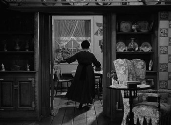 Movie still from “Arsenic and Old Lace” (1944), directed by Frank Capra – An old woman standing in a room looking out a window; Wide shot, High angle