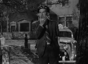 Movie still from “Arsenic and Old Lace” (1944), directed by Frank Capra – An old photo of a man smoking a cigarette in front of an old car; Medium shot, Low angle