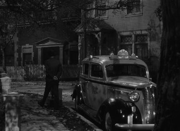 Movie still from “Arsenic and Old Lace” (1944), directed by Frank Capra – An old car parked in front of an old house; Wide shot, High angle