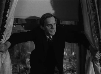 Movie still from “Arsenic and Old Lace” (1944), directed by Frank Capra – A black and white photo of a man in a suit and tie; Medium shot, Low angle