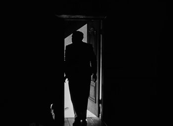 Movie still from “Arsenic and Old Lace” (1944), directed by Frank Capra – A man in a suit walking through a door way; Wide shot, Low angle