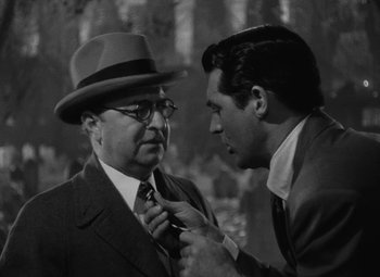 Movie still from “Arsenic and Old Lace” (1944), directed by Frank Capra – A man in a suit and a hat fixing a man's tie; Close Up shot, Over the shoulder angle