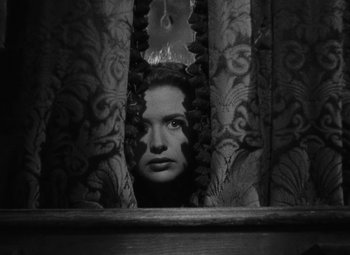 Movie still from “Arsenic and Old Lace” (1944), directed by Frank Capra – A black - and - white photo of a woman peeking through a curtain; Close Up shot, Low angle
