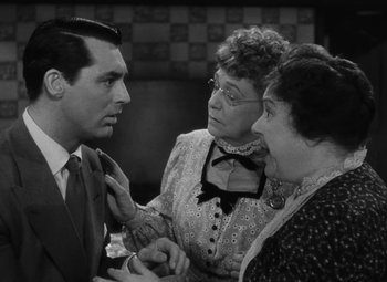Movie still from “Arsenic and Old Lace” (1944), directed by Frank Capra – A man and two women talking to each other; Medium shot, Over the shoulder angle