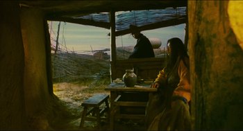 Movie still from “Ashes of Time” (1994), directed by Kar-Wai Wong – A man and a woman sitting at a table in front of an open window; Wide shot, Low angle