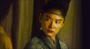 Movie still from “Ashes of Time” (1994), directed by Kar-Wai Wong – A young asian man wearing a black hat; Close Up shot, Over the shoulder angle