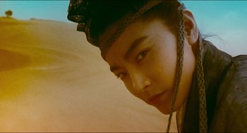Movie still from “Ashes of Time” (1994), directed by Kar-Wai Wong – A young man with a black hat on his head; Close Up shot, Low angle