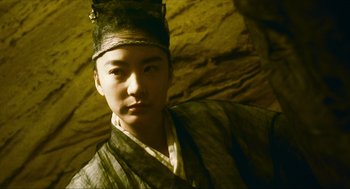 Movie still from “Ashes of Time” (1994), directed by Kar-Wai Wong – A young man wearing a hat and a robe; Close Up shot, Low angle