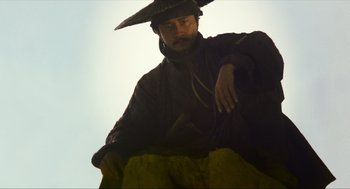 Movie still from “Ashes of Time” (1994), directed by Kar-Wai Wong – A man wearing a hat is sitting in the sunlight; Medium shot, Low angle