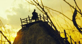 Movie still from “Ashes of Time” (1994), directed by Kar-Wai Wong – A man sitting on top of a hill at sunset; Extreme Wide shot, Low angle