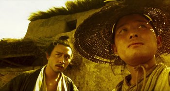 Movie still from “Ashes of Time” (1994), directed by Kar-Wai Wong – Two asian men standing next to each other in front of a building; Close Up shot, Low angle