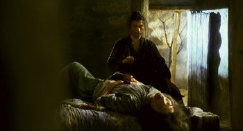 Movie still from “Ashes of Time” (1994), directed by Kar-Wai Wong – A man sitting next to a woman laying on a bed; Medium shot, High angle