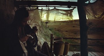Movie still from “Ashes of Time” (1994), directed by Kar-Wai Wong – A man sitting on a ledge next to a cliff; Wide shot, Over the shoulder angle