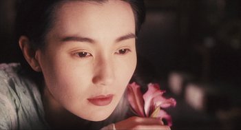 Movie still from “Ashes of Time” (1994), directed by Kar-Wai Wong – A woman holding a pink flower in her hand; Close Up shot, Over the shoulder angle