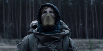 Movie still from “Dark” (2017), created by Baran bo Odar – A man wearing a mask and a raincoat; Medium shot, Low angle