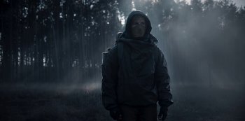 Movie still from “Dark” (2017), created by Baran bo Odar – A man in a hooded jacket standing in the woods; Medium shot, Low angle