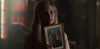 Movie still from “Dark” (2017), created by Baran bo Odar – A young girl holding a picture of a man and a woman; Close Up shot, Over the shoulder angle