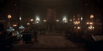 Movie still from “Dark” (2017), created by Baran bo Odar – A man standing in a dark room with candles lit up; Extreme Wide shot, High angle